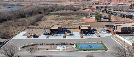 Un hotel con estacionamiento, cancha de tenis y vistas a las montañas.