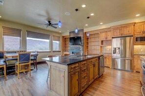 A spacious kitchen with wooden cabinets, a large island, stainless steel appliances, and a ceiling fan. - Luxury Vacation Home M21 - 3 Master suites and 3.5 bathrooms (Moab)