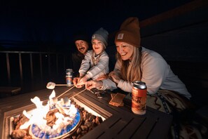 A group of people roasting marshmallows over a fire pit on a deck. - Luxury Vacation Home M21 - 3 Master suites and 3.5 bathrooms (Moab)