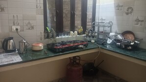 A kitchen with a gas stove, a kettle, a gas cylinder, and various kitchen utensils. - We are not a commercial hotel... we are your home (Munsyari)