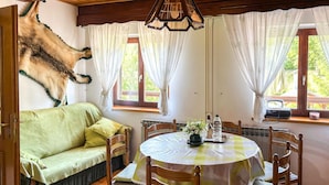 A cozy room with a green sofa, wooden dining table, and a hanging animal decoration.