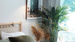 A bedroom with a bed, a potted plant, a wall-mounted picture, and a window with curtains. - Bees Beach House: Luxury 5BR Sturgeon Lakefront w/ Private Sandy Beach & Sauna (Kawartha Lakes)