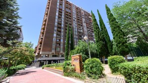 A tall residential building with multiple balconies, surrounded by greenery and a paved walkway. - 2-bedroom, 2-bathroom flat near the Bernabéu (Madrid)