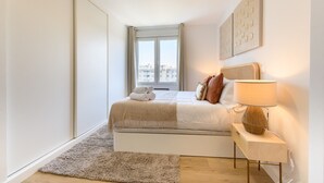 A bedroom with a bed, a bedside lamp, a window, and a view of buildings. - 2-bedroom, 2-bathroom flat near the Bernabéu (Madrid)