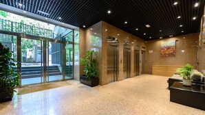 A lobby with a reception desk, two elevators, a glass door entrance, and potted plants. - 2-bedroom, 2-bathroom flat near the Bernabéu (Madrid)