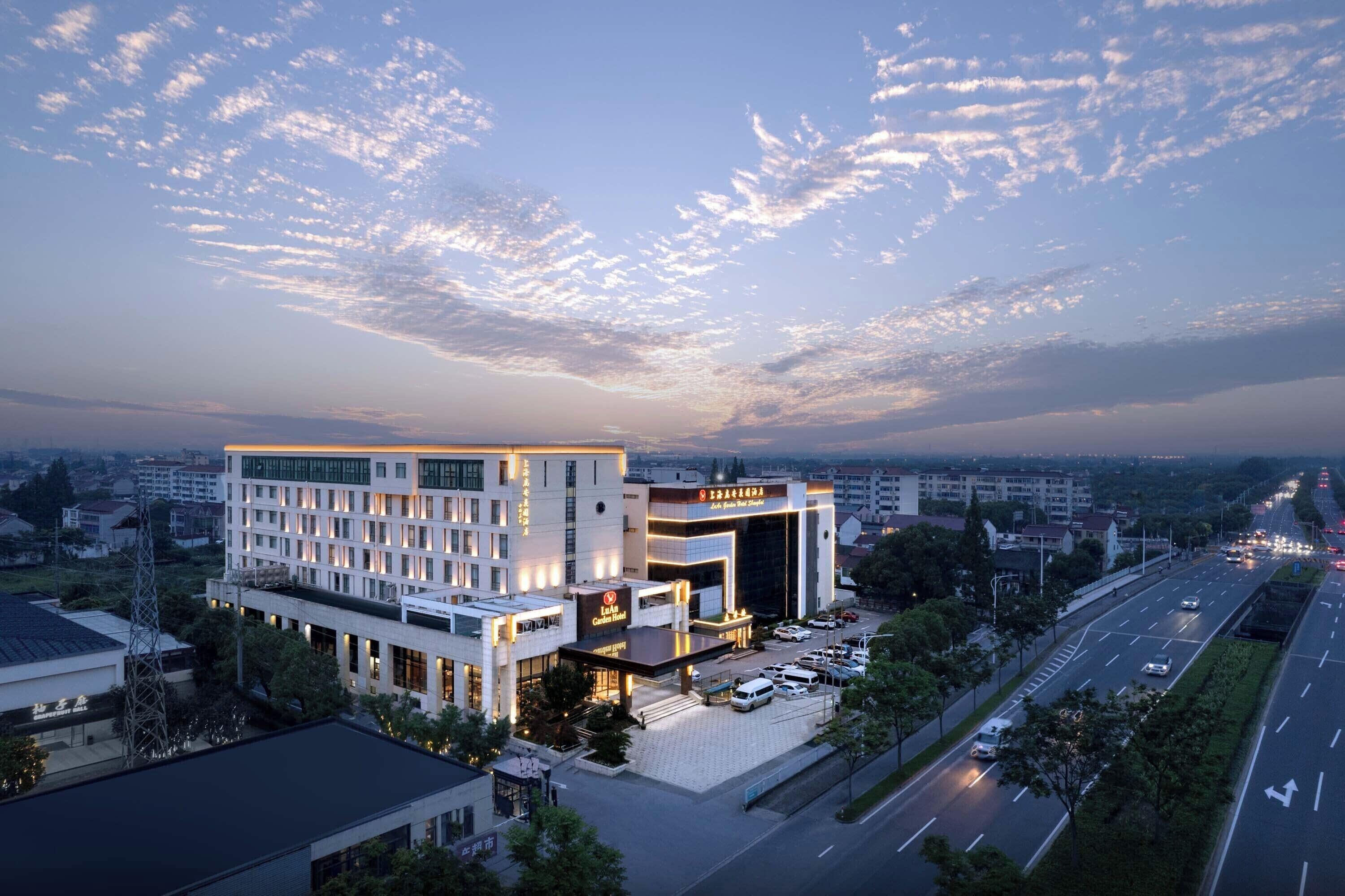 A modern hotel with a prominent entrance, multiple floors, and a parking lot.