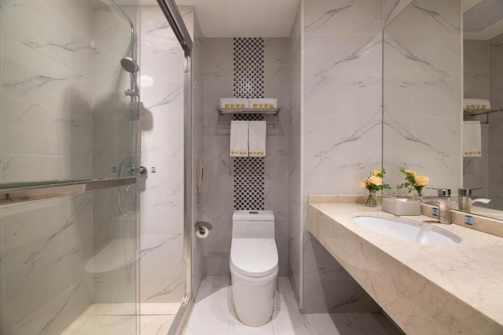 Une salle de bain avec une douche à parois de verre, des toilettes, un lavabo et un miroir.