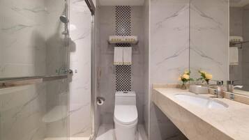 Une salle de bain avec une douche à parois de verre, des toilettes, un lavabo et un miroir.