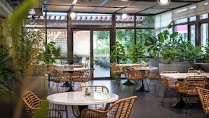 An indoor dining area with round tables, wicker chairs, and large windows allowing natural light. - Lu'an Garden Hotel Shanghai (Shanghai)