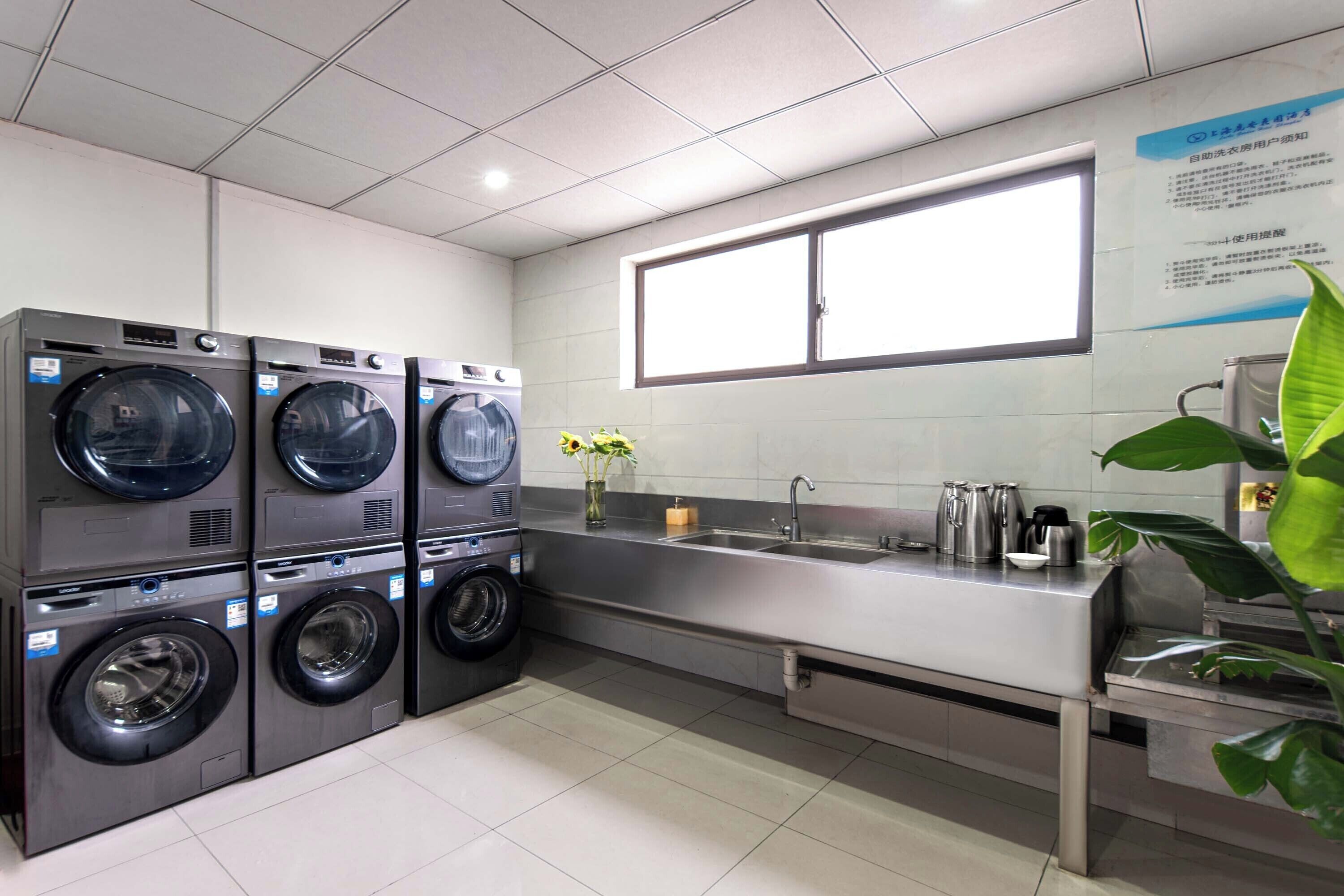 A laundry facility with multiple washing machines, a sink, and a window.