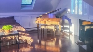 A room with a piano, a bed with a plant, a skylight, and a fireplace. - Villa Sabrina (Lagrangeville)