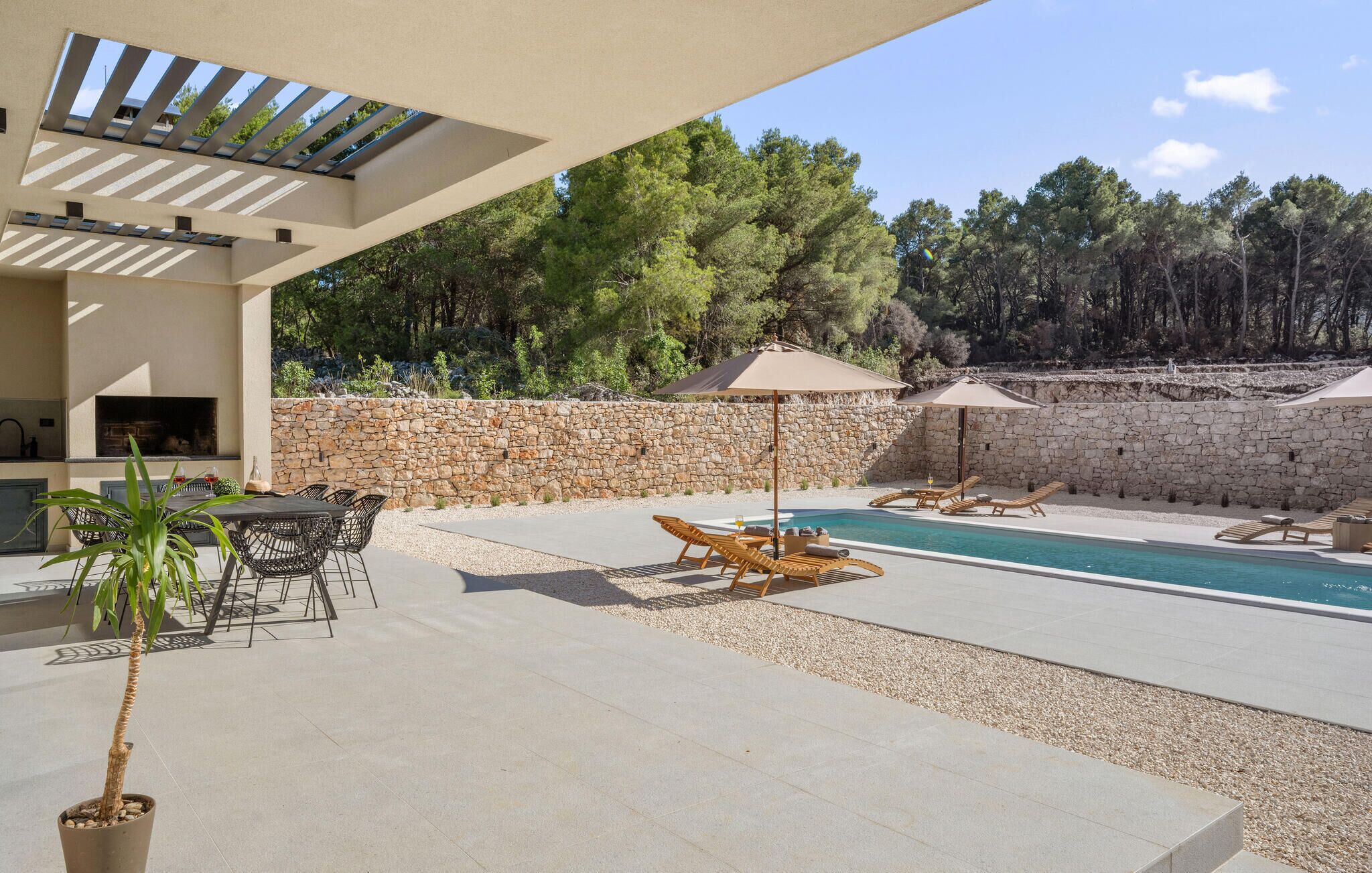 A pool area with lounge chairs, a table, and a grill.