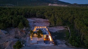 Un edificio moderno con tetto piano, immerso in una fitta foresta e con una vista aperta sul paesaggio circostante.