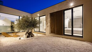 Un edificio moderno con ampie finestre, un albero e un'area con ghiaia.