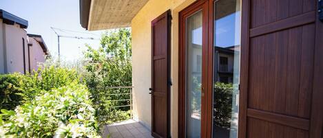 A residential building with a wooden door, a sliding glass door, and a tiled patio area.