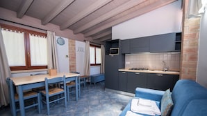 Una cocina compacta con zona de comedor, un sofá azul y una pequeña mesa.