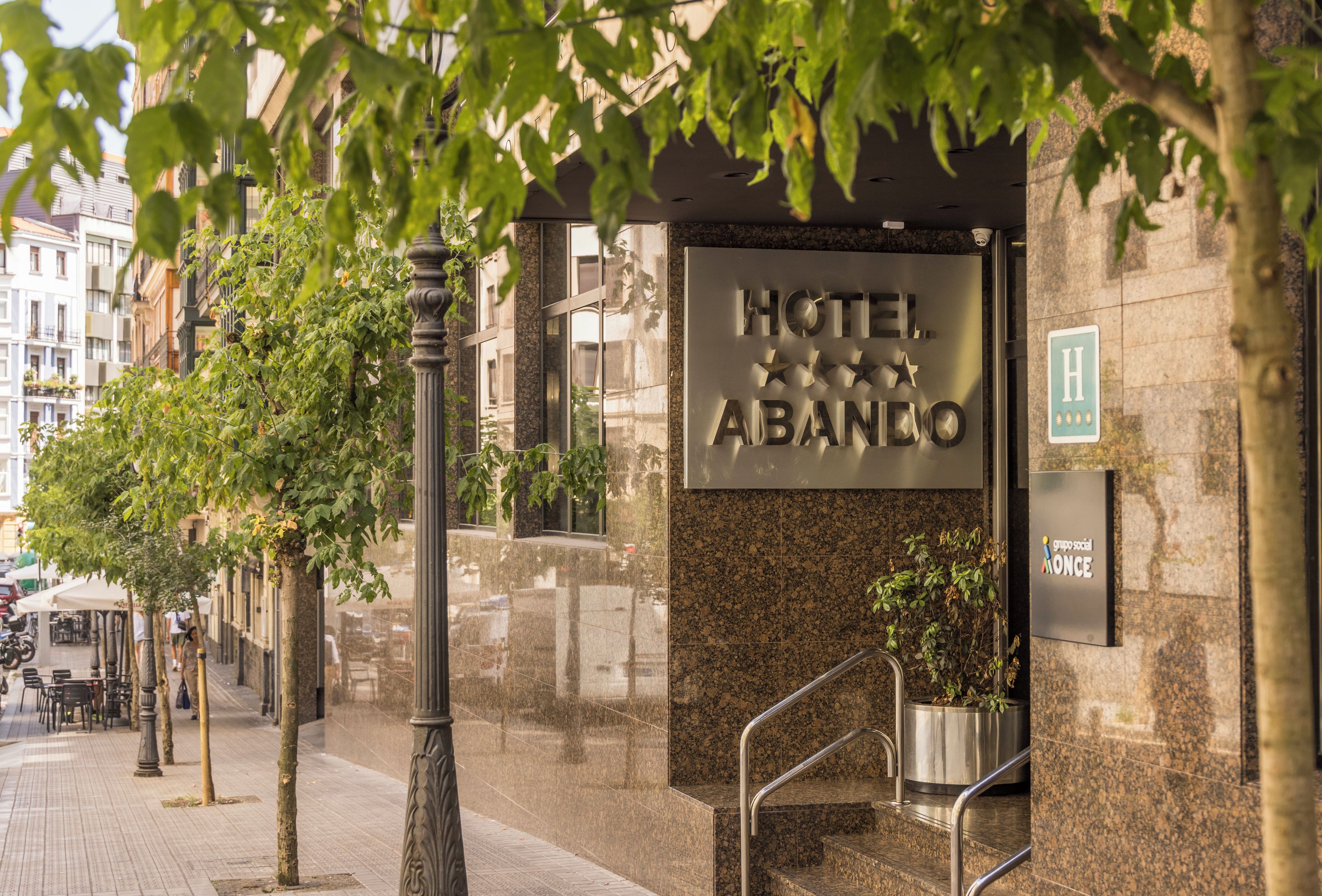 Een hotelentree met een bord waarop 'HOTEL ABANCO' staat en een 'H'-bord dat de ingang aangeeft.