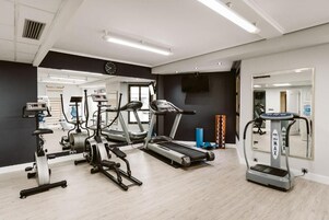 Uma academia com esteiras, elípticos e equipamentos de musculação.