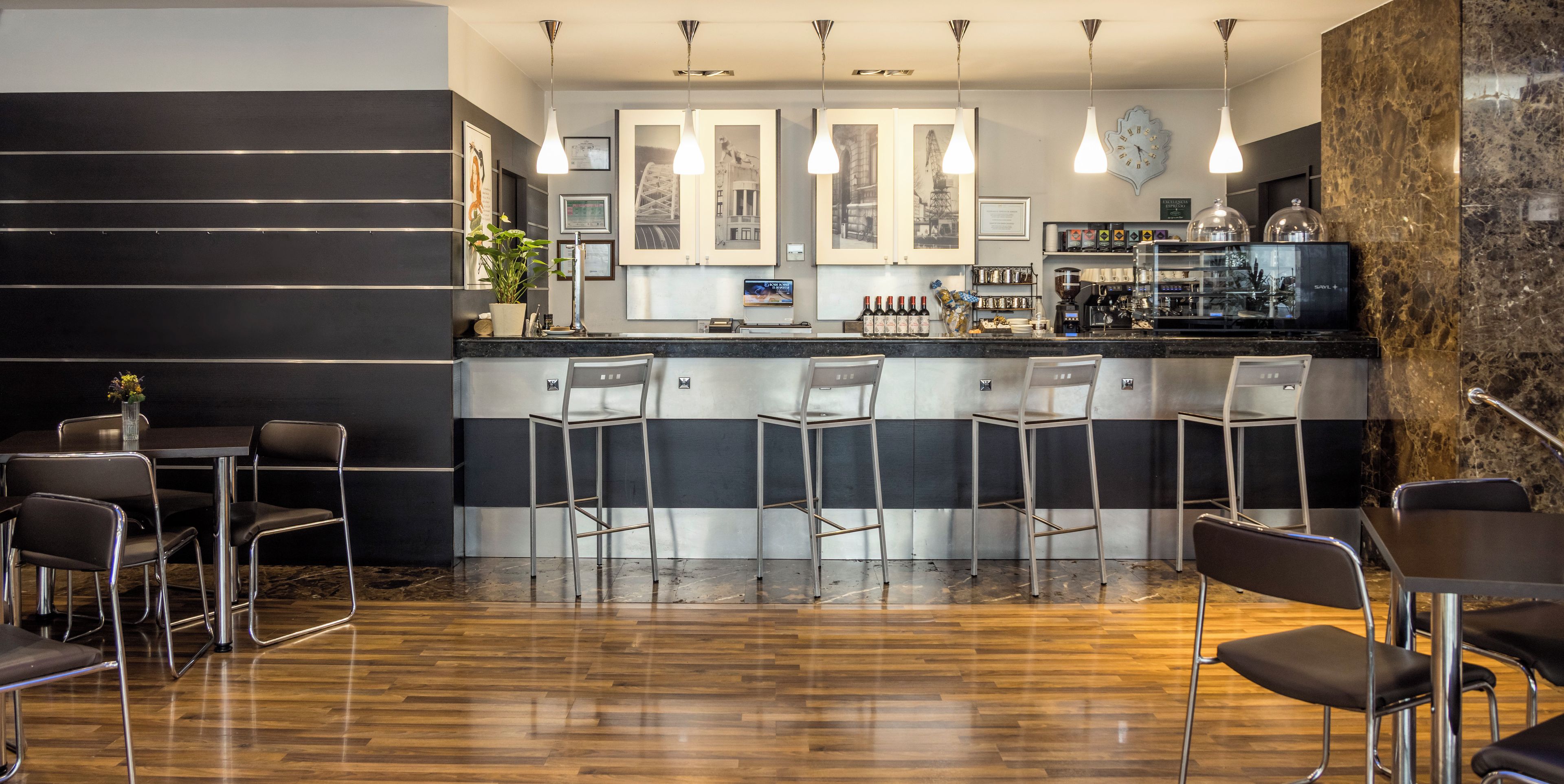 A modern bar area with a counter, bar stools, and a coffee machine.