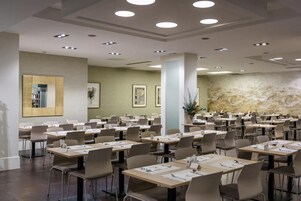 Una sala conferenze con diversi tavoli e sedie, luci a soffitto e opere d'arte appese alle pareti.