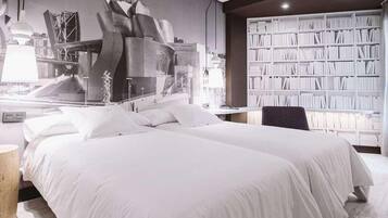 Une chambre d’hôtel moderne avec un grand lit, une bibliothèque et une fresque murale représentant un paysage urbain.