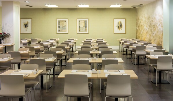 Un salón de conferencias con varias mesas y sillas, equipado con tarjetas de identificación y material de escritura.