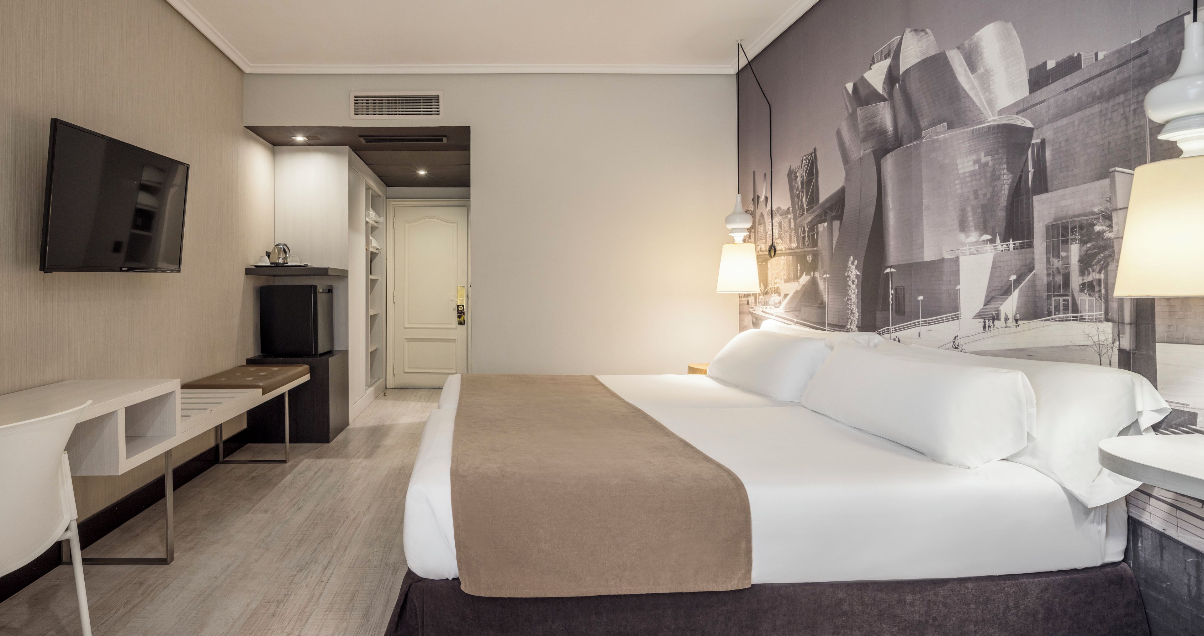 Una habitación de hotel con una cama, un escritorio, un televisor y un mural grande en la pared.
