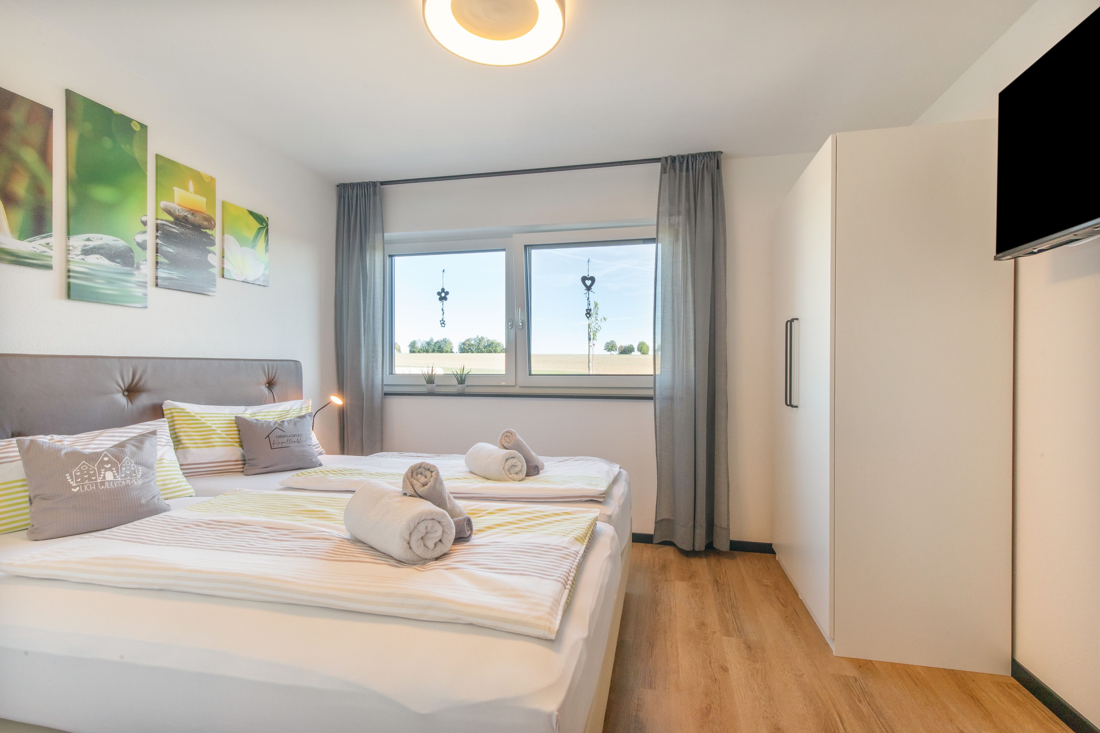 Quarto de hotel com uma cama, televisão e janela com cortinas.