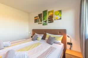 Ein Hotelzimmer mit einem Bett, Kissen, einem Nachttisch, einer Lampe und Wandbildern.