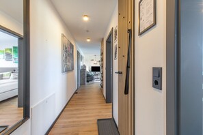 Ein Flur mit Holzboden, einer Tür inklusive Griff und einer Wandleuchte.