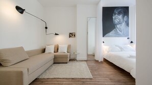 Ett modernt sovrum med en soffa, en säng, ett litet sidobord och en tavla på väggen.