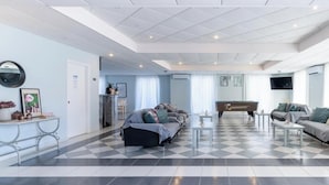 Un salón amplio con suelo a cuadros, sofás, una mesa de centro y una televisión.