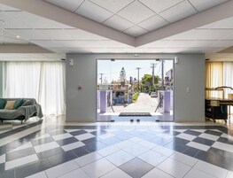 Una hall d'albergo con pavimento a scacchi, un divano e vista sulla strada.