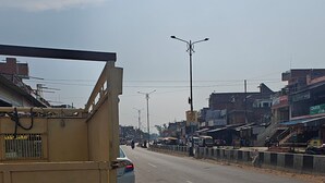Una calle con un camión amarillo, edificios y cielo despejado.