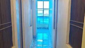 Un pasillo con baldosas estampadas, puertas y ventanas con rejas.