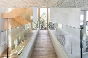 Ein modernes Interieur mit Holzboden, Glasgeländern und Blick auf Grünfläche.