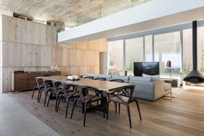 Een modern interieur met een eethoek, bank, televisie en houten kasten.