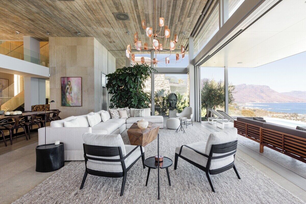 Una sala moderna con un sofá seccional grande, una mesa de centro y dos sillones. Una ventana grande ofrece vistas al exterior.