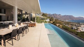 Ein moderner Essbereich im Freien mit Pool und Blick auf eine Berglandschaft.