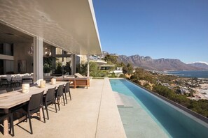 A modern outdoor dining area with a pool overlooking a mountainous landscape. - Obsidian (Cape Town)