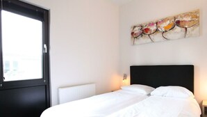 A hotel room with a bed, a window, a radiator, and a painting on the wall. - Holiday Home in Nijkerk With Terrace (Nijkerk)