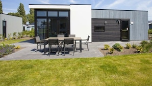 A modern building with a patio area featuring a table and chairs. - Holiday Home in Nijkerk With Terrace (Nijkerk)