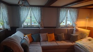 Une pièce comprenant un canapé d’angle, un lit et une fenêtre avec des rideaux.