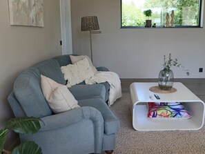 Ein Wohnzimmer mit einem grauen Sofa, einem weißen Couchtisch und einer Stehlampe.