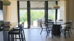 A modern kitchen with a dining area, large sliding glass doors leading to a patio, and a view of greenery outside. - 5 Star Holiday Home in Falkenberg (Falkenberg)