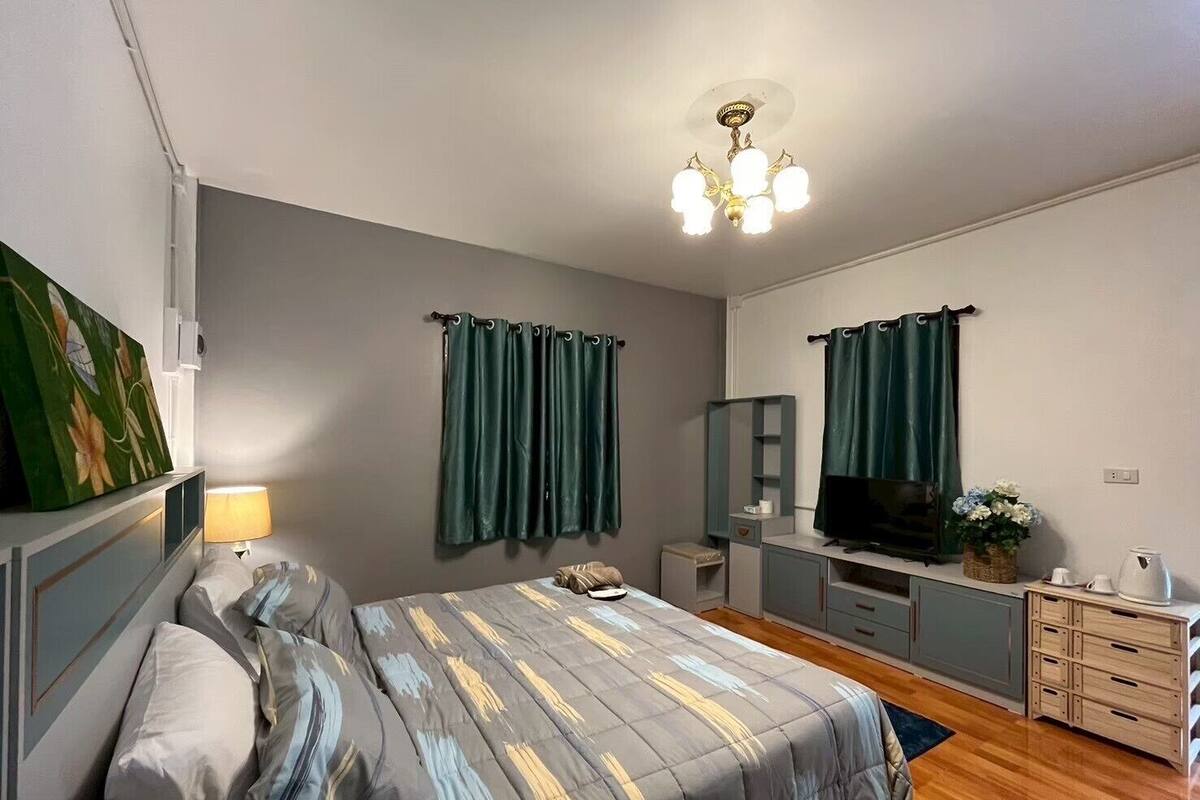 A bedroom with a bed, a TV, a desk, and a mirror.