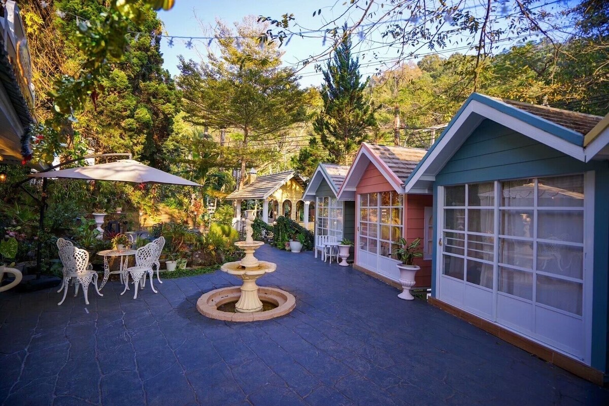 A courtyard with a fountain, outdoor seating, and colorful buildings.