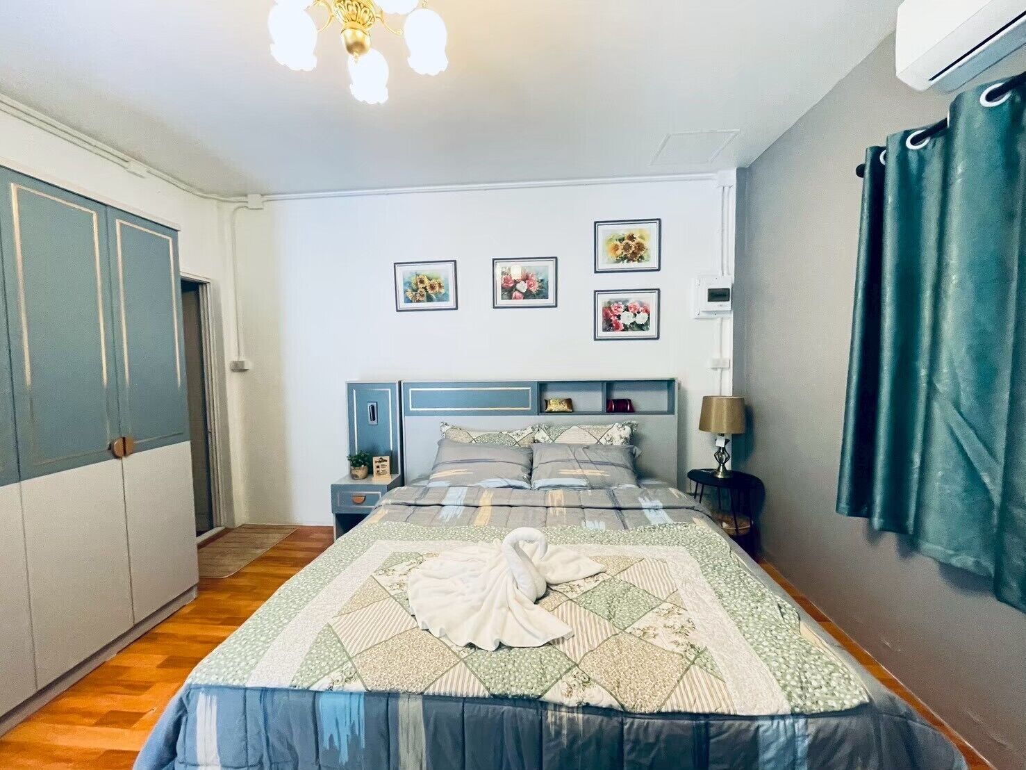 Une chambre à coucher avec un lit, des tables de chevet, une lampe, une armoire et des tableaux encadrés accrochés au mur.
