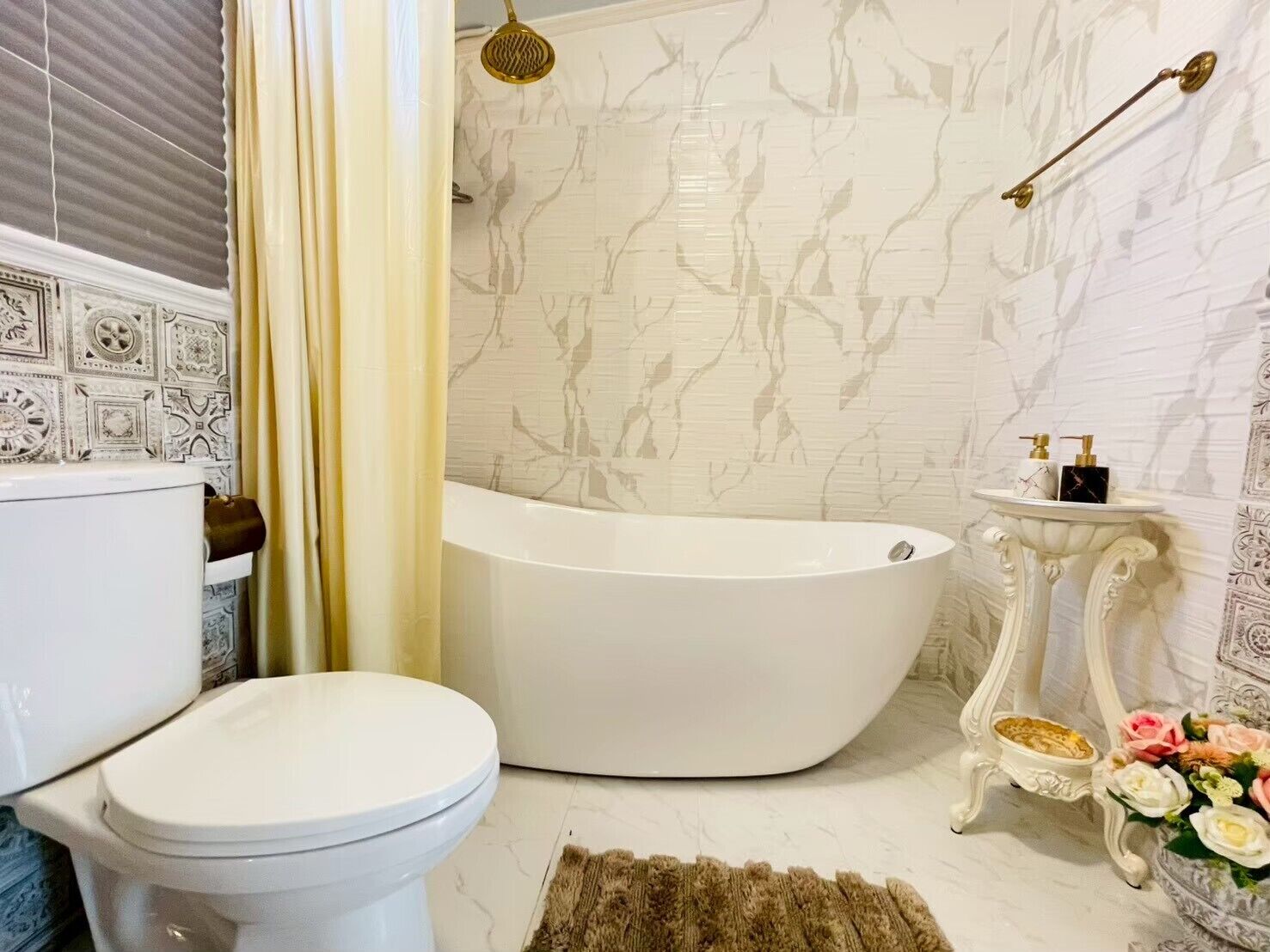 A bathroom with a freestanding bathtub, a toilet, a vanity with a mirror, and a shower curtain.