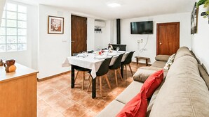 A dining area with a table set for four, a sofa, and a television on the wall.